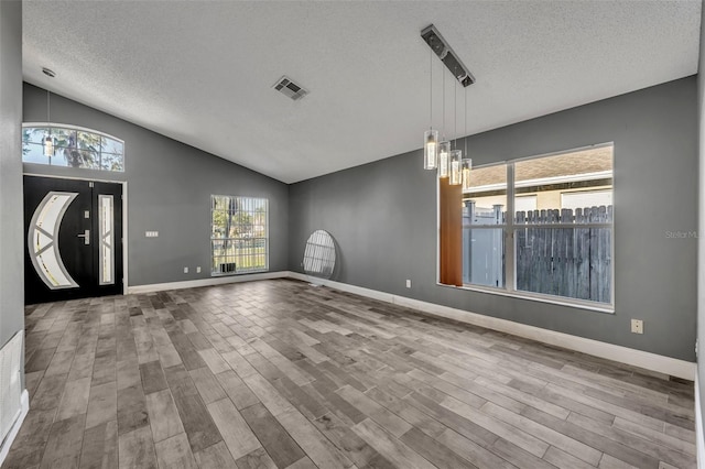 entryway with visible vents, lofted ceiling, wood finished floors, an inviting chandelier, and a textured ceiling