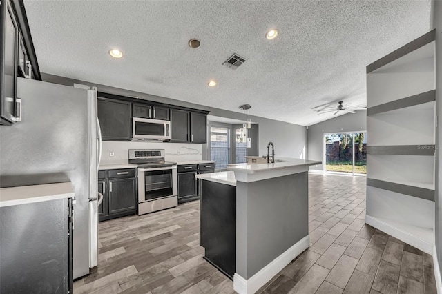 kitchen with visible vents, appliances with stainless steel finishes, vaulted ceiling, light countertops, and light wood-type flooring