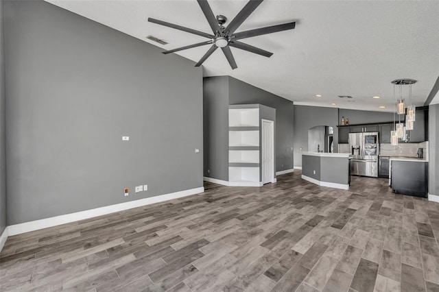 unfurnished living room with lofted ceiling, wood finished floors, visible vents, baseboards, and a ceiling fan