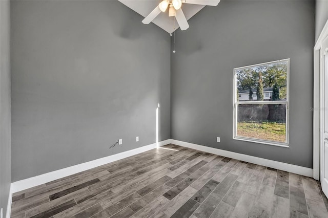 spare room with high vaulted ceiling, a ceiling fan, baseboards, and wood finished floors