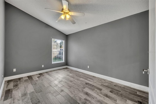 spare room featuring lofted ceiling, a textured ceiling, wood finished floors, and a ceiling fan