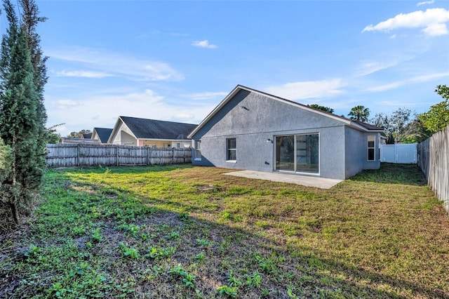 back of property featuring a fenced backyard, a lawn, and stucco siding