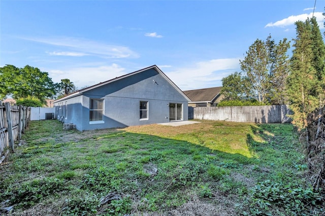 back of property with a fenced backyard, a yard, and stucco siding