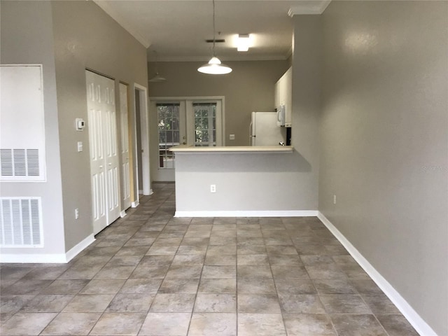 kitchen with a peninsula, visible vents, freestanding refrigerator, decorative light fixtures, and crown molding