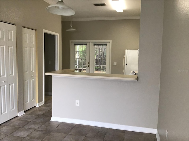 kitchen featuring baseboards, visible vents, freestanding refrigerator, crown molding, and pendant lighting