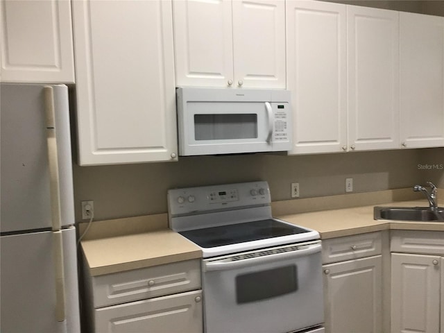 kitchen featuring light countertops, white appliances, white cabinets, and a sink