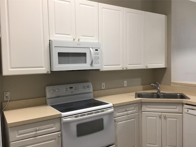 kitchen with white appliances, white cabinets, and a sink