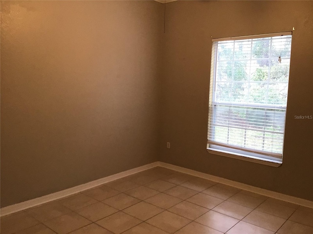 empty room with baseboards and light tile patterned flooring