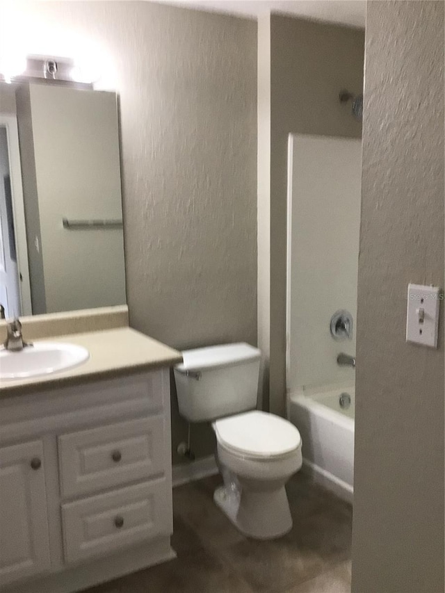 bathroom featuring washtub / shower combination, a textured wall, vanity, and toilet