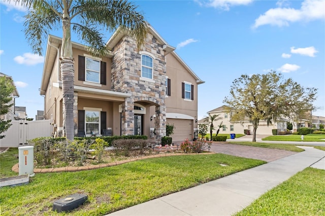 view of front facade with a garage, stone siding, stucco siding, fence, and a front yard