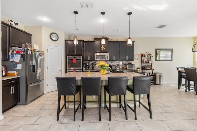 kitchen with stainless steel appliances, a breakfast bar area, visible vents, and decorative backsplash