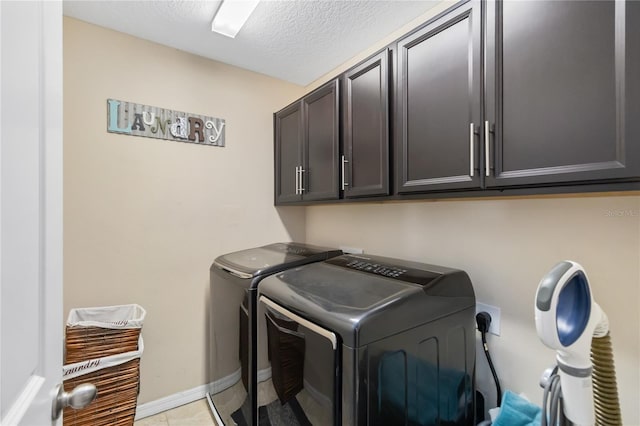 laundry area with light tile patterned floors, cabinet space, a textured ceiling, washer and dryer, and baseboards