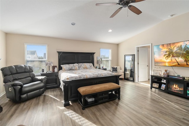 bedroom featuring vaulted ceiling, ceiling fan, multiple windows, and wood finished floors