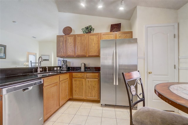 kitchen with light tile patterned floors, dark countertops, appliances with stainless steel finishes, vaulted ceiling, and a sink