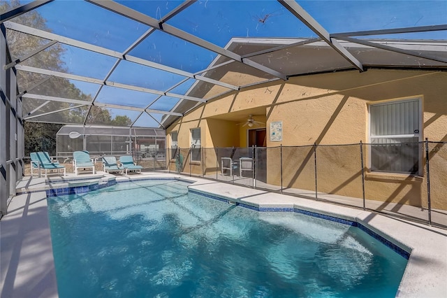 view of swimming pool with a ceiling fan, glass enclosure, a patio area, and a pool with connected hot tub