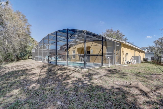 rear view of property featuring a lanai, stucco siding, an outdoor pool, and central air condition unit