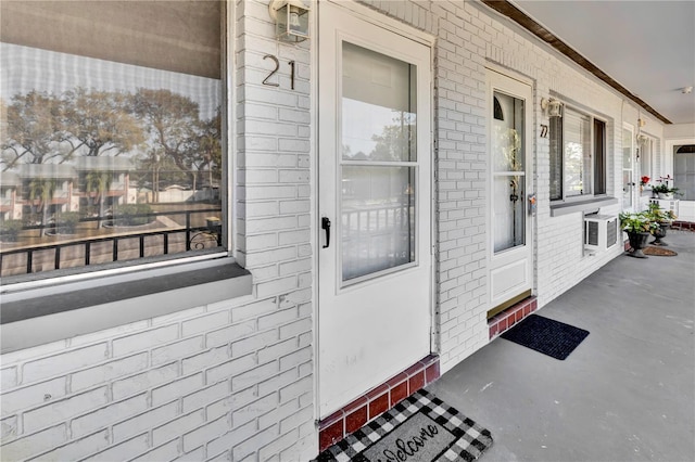 view of exterior entry featuring a wall unit AC and brick siding