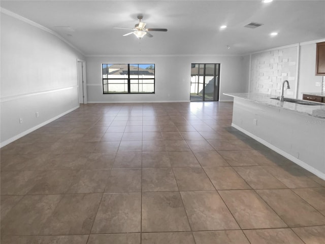 unfurnished living room with dark tile patterned floors, a sink, visible vents, a ceiling fan, and ornamental molding