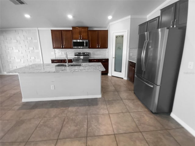 kitchen with a kitchen island with sink, appliances with stainless steel finishes, light stone counters, and a sink