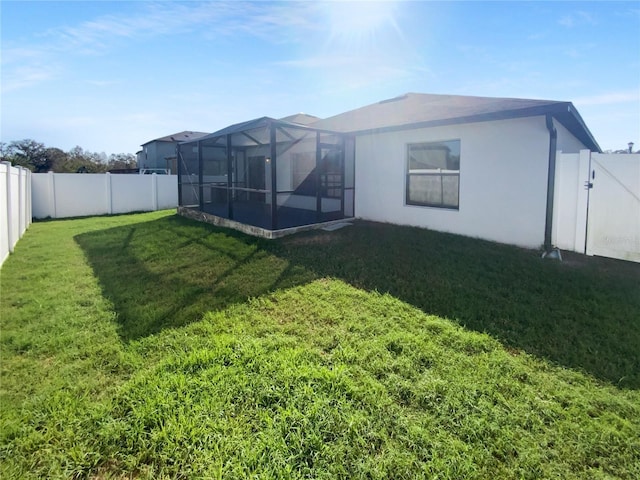 back of house featuring a yard, stucco siding, a gate, a lanai, and a fenced backyard