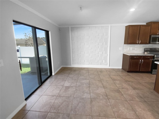 kitchen featuring crown molding, stainless steel appliances, tasteful backsplash, light countertops, and baseboards