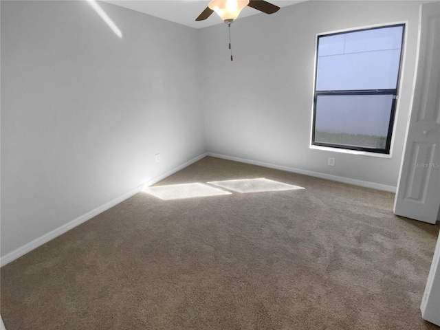 carpeted spare room with ceiling fan and baseboards