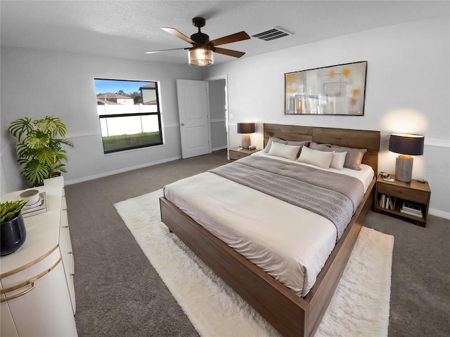 bedroom with a textured ceiling, a ceiling fan, visible vents, baseboards, and dark carpet