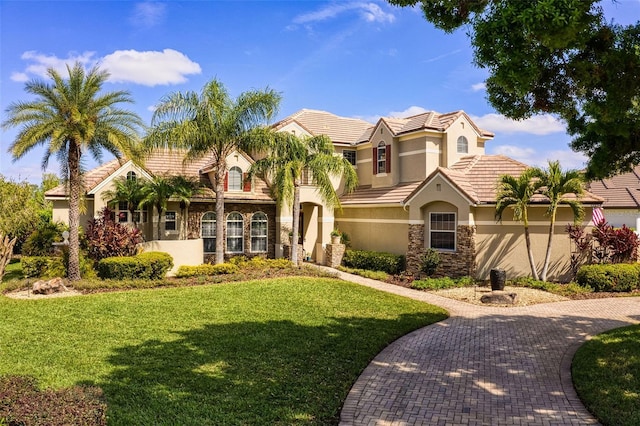 mediterranean / spanish-style home featuring stone siding, a front lawn, a tile roof, and stucco siding