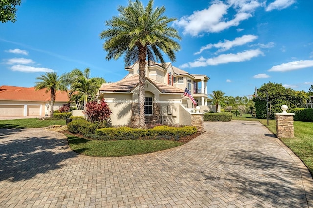 view of front facade featuring a tiled roof, decorative driveway, and stucco siding