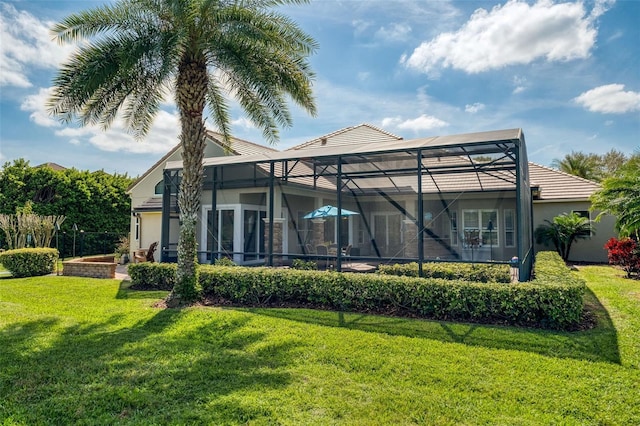 rear view of house featuring glass enclosure, a yard, and stucco siding