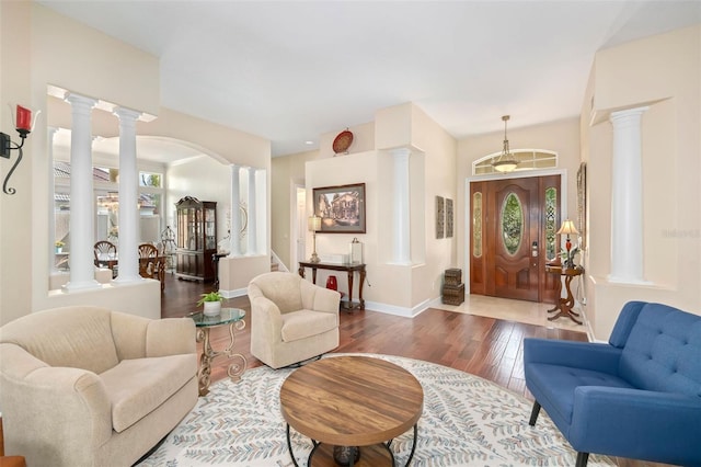 living room featuring decorative columns, baseboards, and wood-type flooring