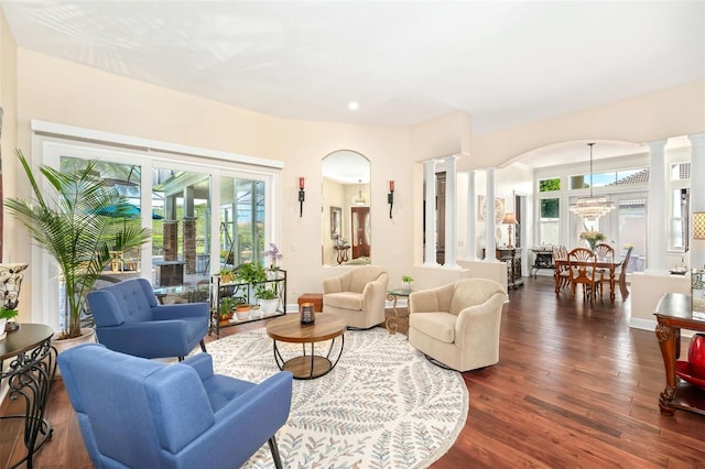 living area with an inviting chandelier, decorative columns, baseboards, and dark wood finished floors