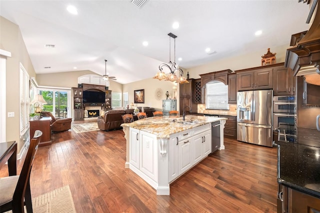 kitchen featuring dark brown cabinetry, stainless steel appliances, a sink, white cabinets, and an island with sink