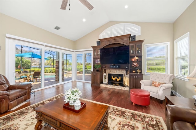 living area featuring a high end fireplace, plenty of natural light, visible vents, and dark wood finished floors