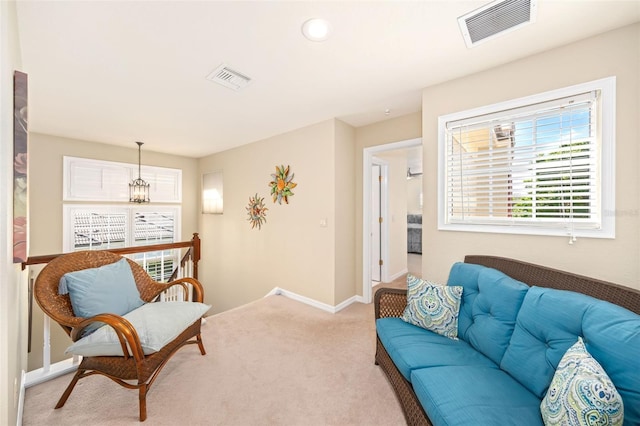 living area with light carpet, baseboards, visible vents, and a chandelier