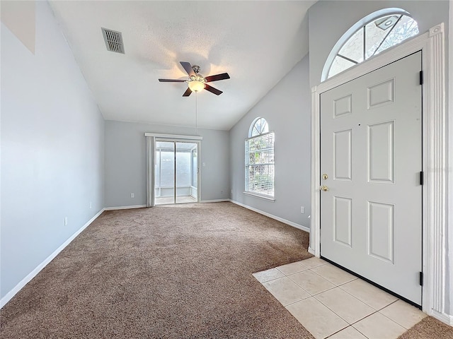 foyer featuring ceiling fan, light carpet, visible vents, baseboards, and vaulted ceiling