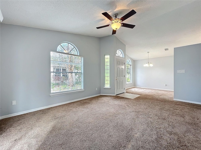 carpeted empty room with a textured ceiling, vaulted ceiling, and a wealth of natural light