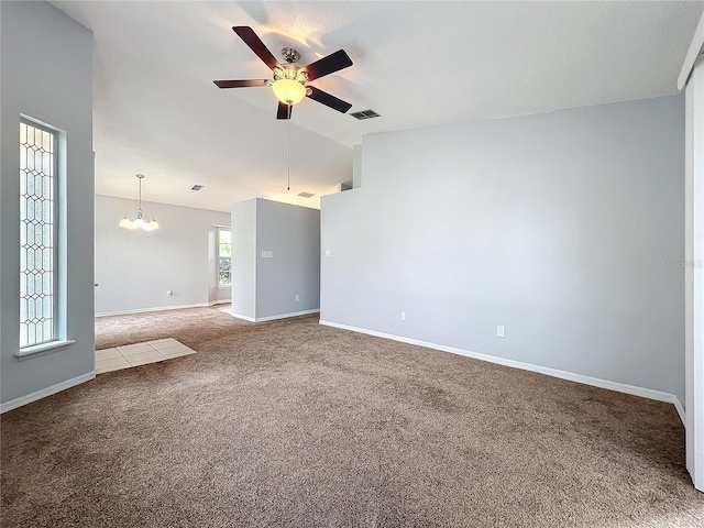 spare room featuring baseboards, visible vents, lofted ceiling, carpet flooring, and ceiling fan with notable chandelier