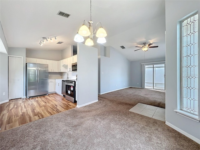 kitchen featuring stainless steel appliances, light countertops, open floor plan, white cabinets, and light carpet