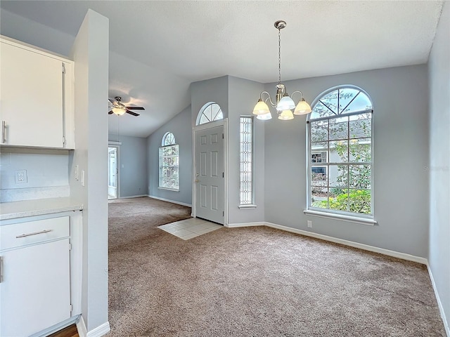 entryway featuring a healthy amount of sunlight, baseboards, vaulted ceiling, and light colored carpet