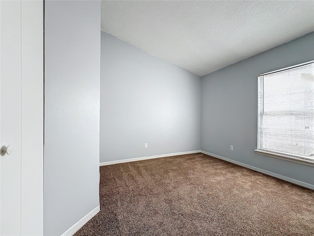 carpeted spare room with a textured ceiling, lofted ceiling, and baseboards