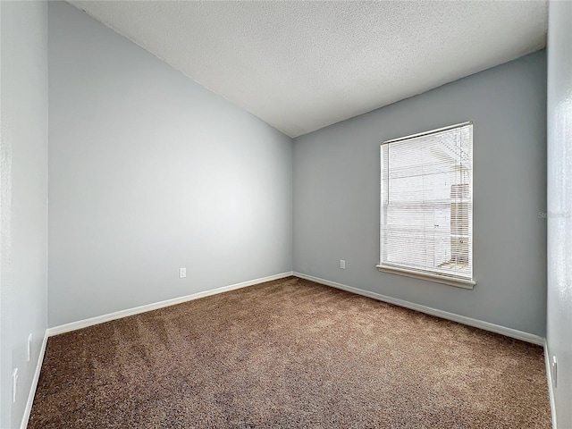 carpeted empty room featuring baseboards, vaulted ceiling, and a textured ceiling