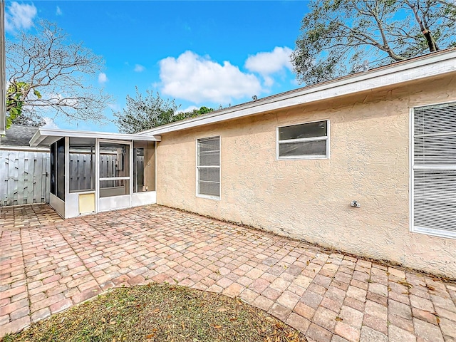 back of house with a patio area, a sunroom, and stucco siding