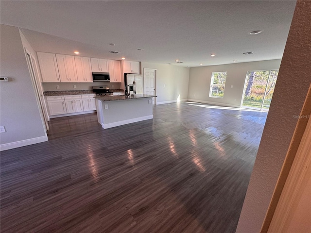 kitchen with stainless steel appliances, dark wood-type flooring, white cabinetry, open floor plan, and an island with sink