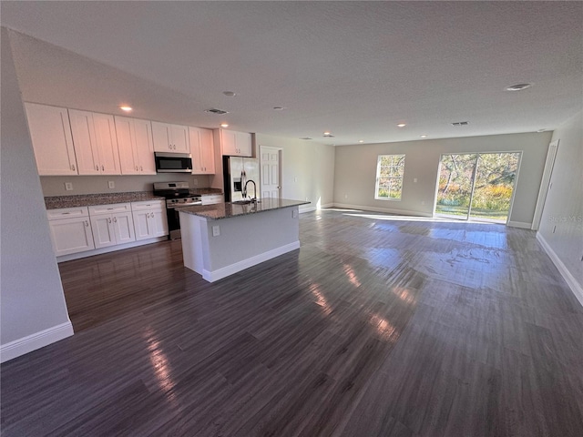 kitchen featuring an island with sink, white cabinetry, stainless steel appliances, and open floor plan