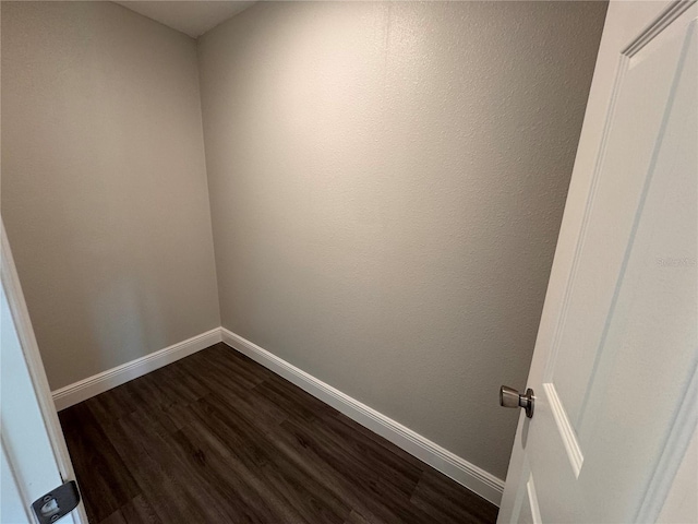 spare room featuring dark wood-style floors and baseboards