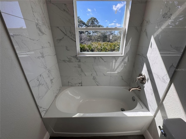 bathroom with a textured wall and shower / washtub combination