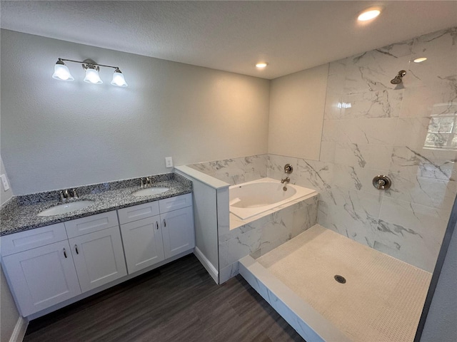 bathroom featuring a bath, double vanity, a sink, and wood finished floors