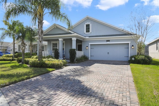 view of front of home with a porch, a garage, decorative driveway, stucco siding, and a front yard