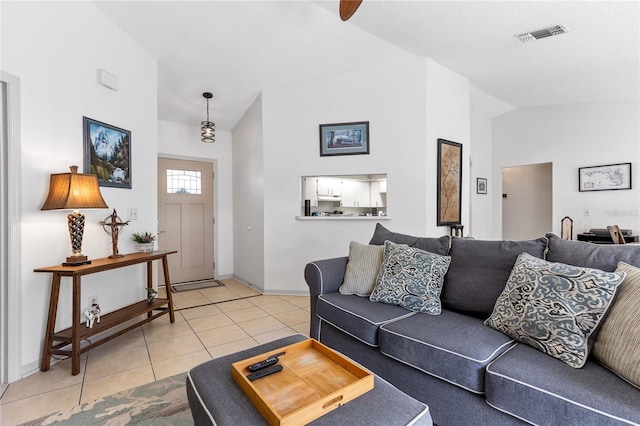 living room with light tile patterned floors, visible vents, high vaulted ceiling, and baseboards